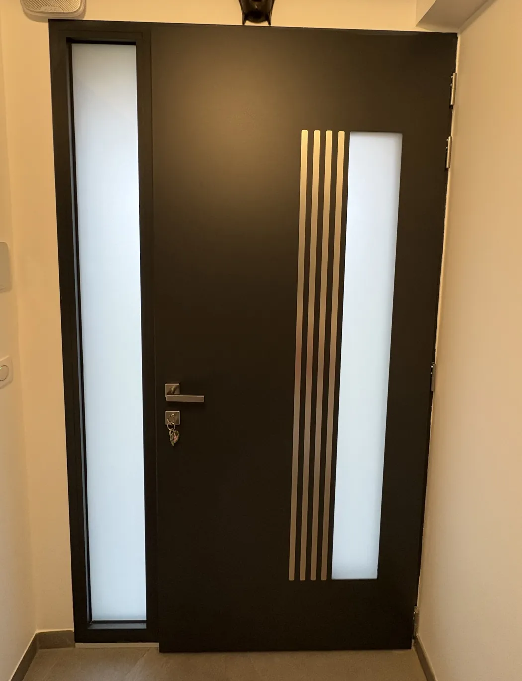 Porte d’entrée en aluminium anthracite à inserts verticaux, posée par Porteclose